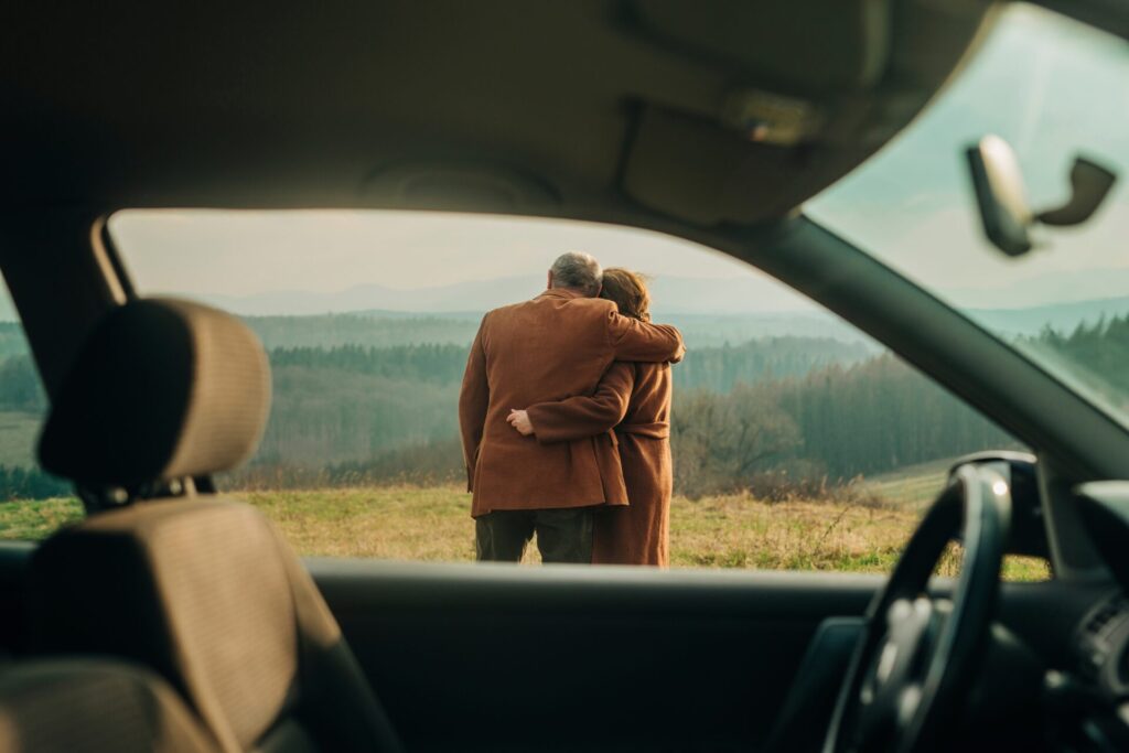 Happy,Senior,Couple,Hugging,Each,Other,Seen,Through,Car,Window