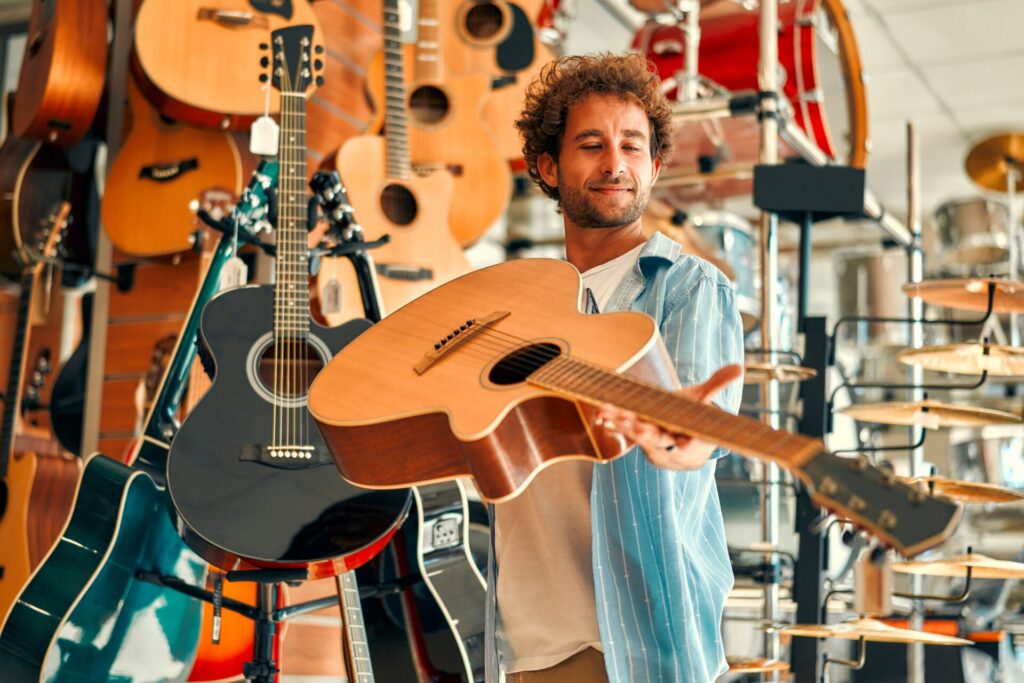 Handsome,Bearded,Curly,Man,Choosing,A,Guitar,In,A,Musical