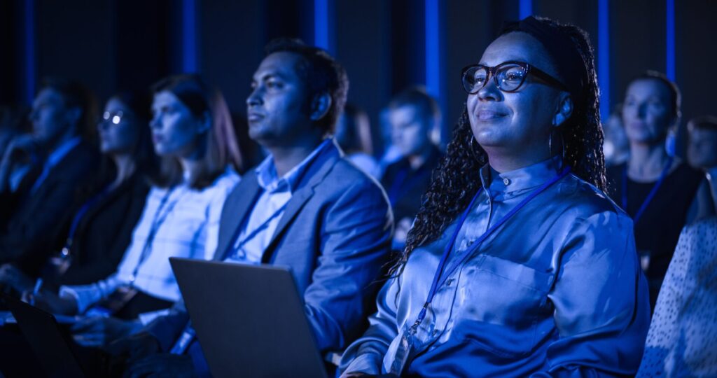 Black,Female,Sitting,In,Dark,Crowded,Auditorium,At,An,International