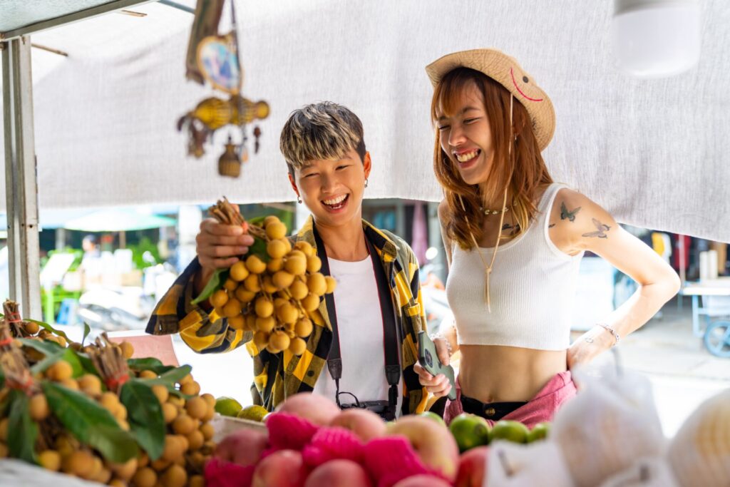 Asian,Woman,Friends,Buying,And,Eating,Street,Food,Fresh,Fruit