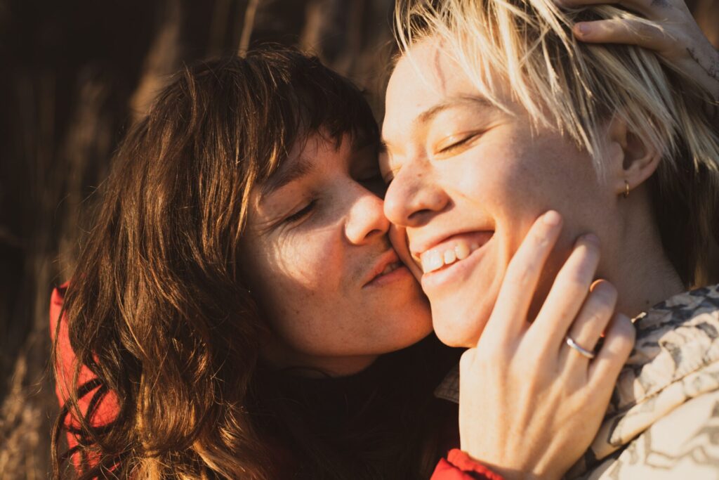 Sweet,Queer,Couple,Cuddle,In,Sunshine,On,Winter,Hike,In