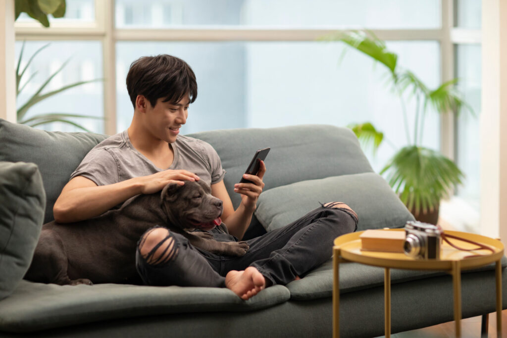 Young,Chinese,Man,With,Pet,Dog,On,Sofa