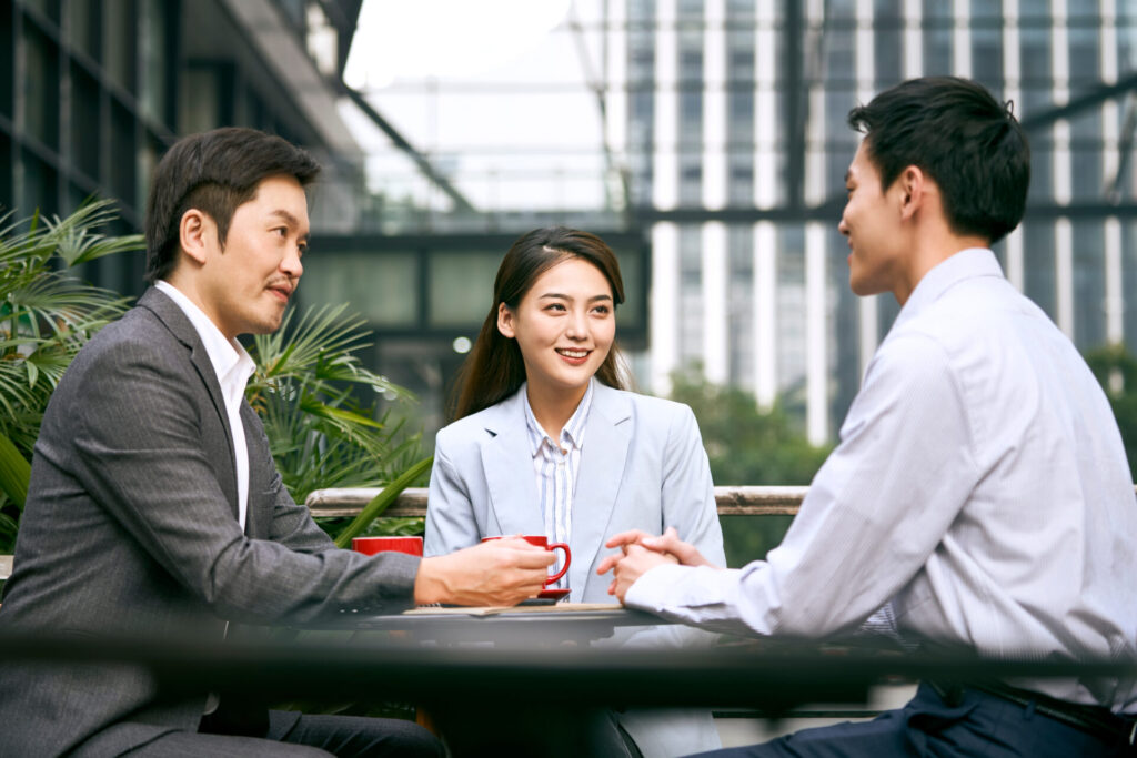 Three,Asian,Corporate,Businesspeople,Discussing,Business,Outdoors,In,Coffee,Shop